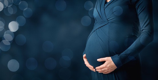 pregnancy and maternity concept. Woman caress her pregnant belly. Wide banner composition with bokeh in background.